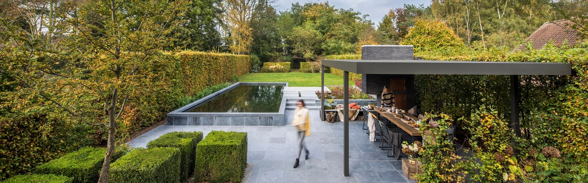 Renson Algarve lamellen overkapping in herfsttuin met vijver en buitenkeuken