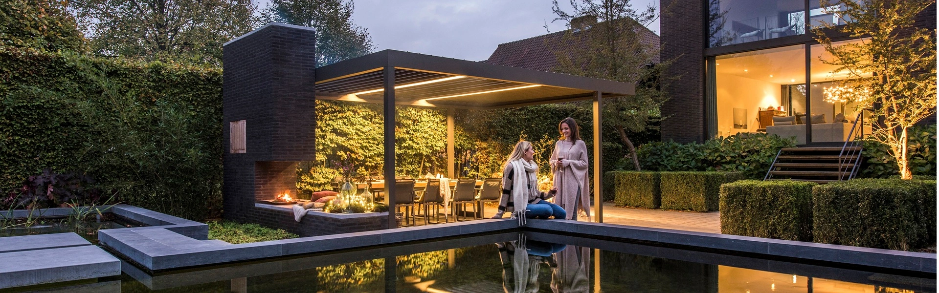 Renson Algarve lamellen overkapping met sfeerverlichting en haard bij schemering