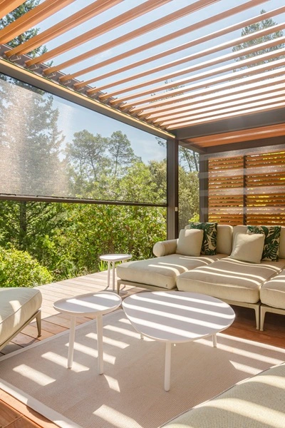 Renson Camargue lamellen overkapping met loungeset en houten zijpanelen Renson Camargue lamellen overkapping met loungeset en houten zijpanelen