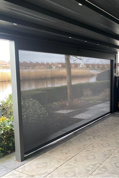 Ritsscreen op terrasoverkapping met uitzicht op tuin en water Ritsscreen op terrasoverkapping met uitzicht op tuin en water