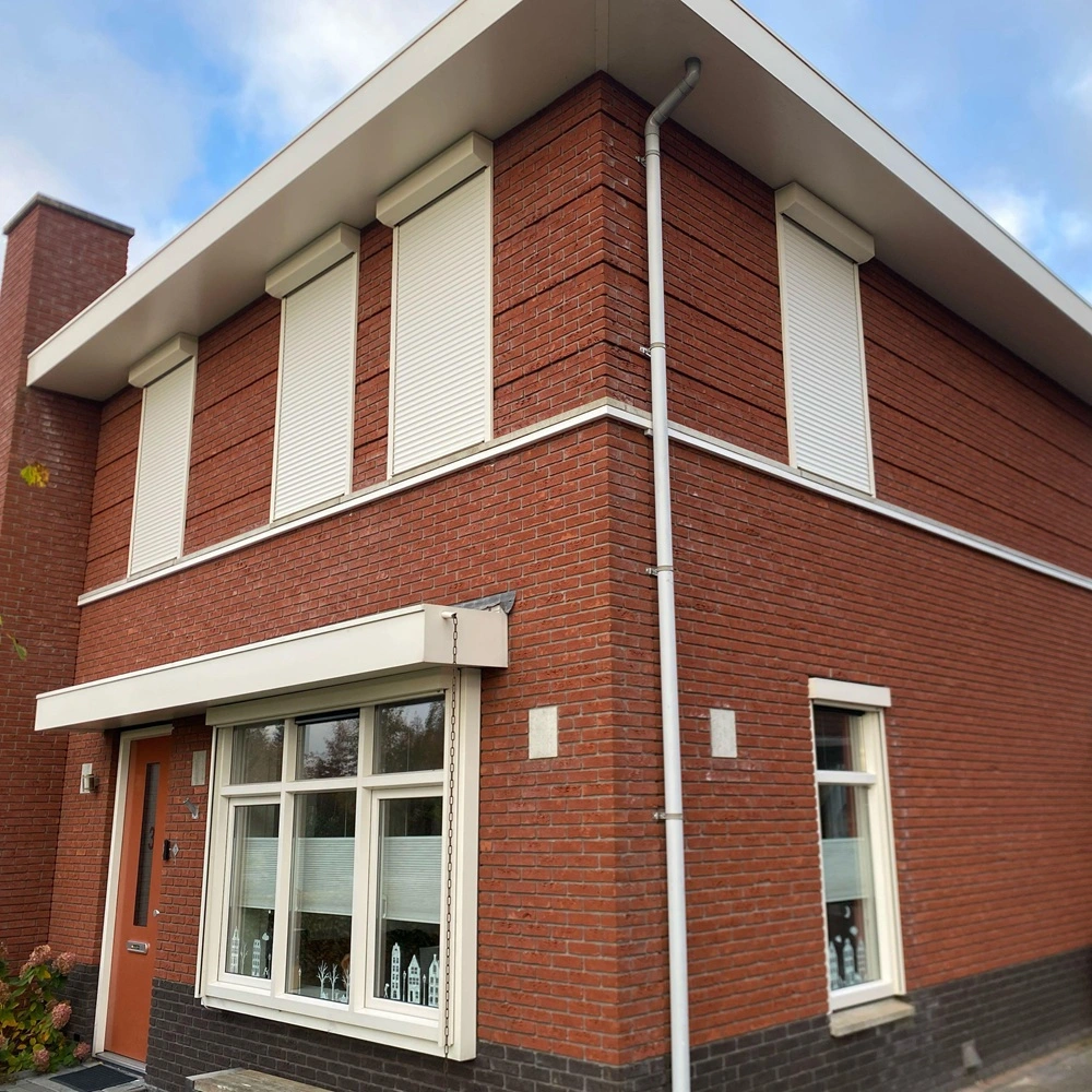 Rode bakstenen woning met vier witte rolluiken Rode bakstenen woning met vier witte rolluiken