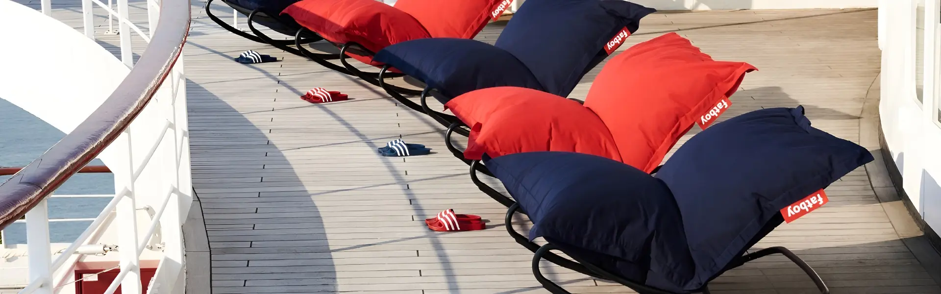 Rode en blauwe outdoor schommelstoelen met comfortabele kussens op een scheepsdek