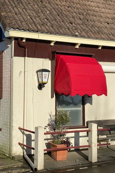 Rode houten markies op karakteristieke woninggevel Rode houten markies op karakteristieke woninggevel