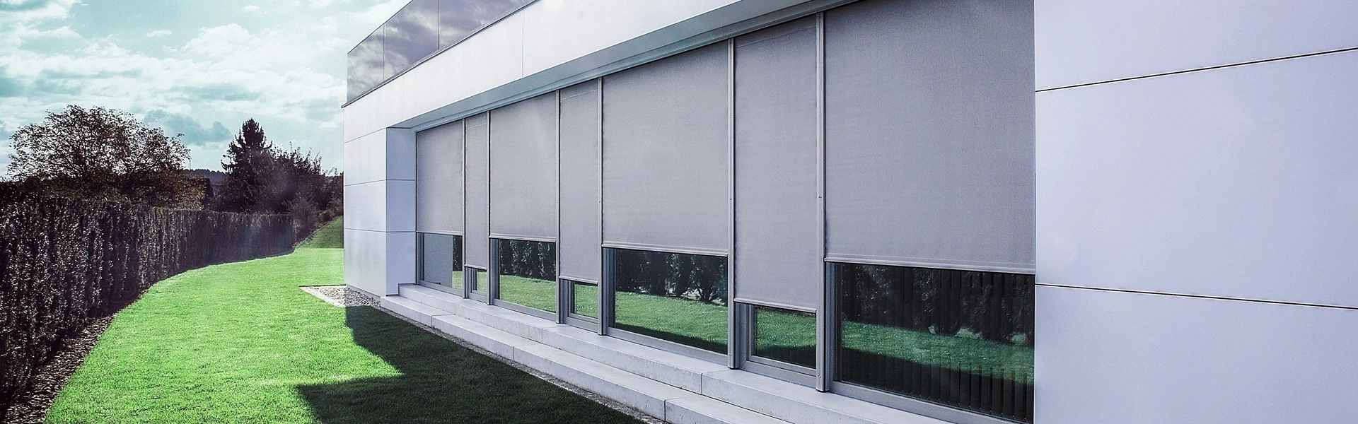 RolSCREEN2 zonwering op moderne villa met grote ramen en groen gazon