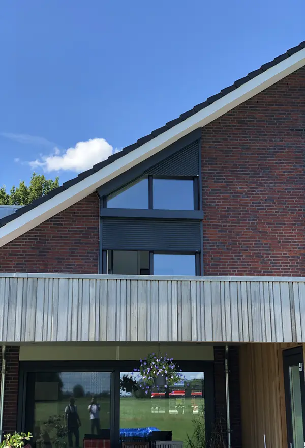 Rolluiken op schuine gevel van een woning met rood baksteen en hout Rolluiken op schuine gevel van een woning met rood baksteen en hout