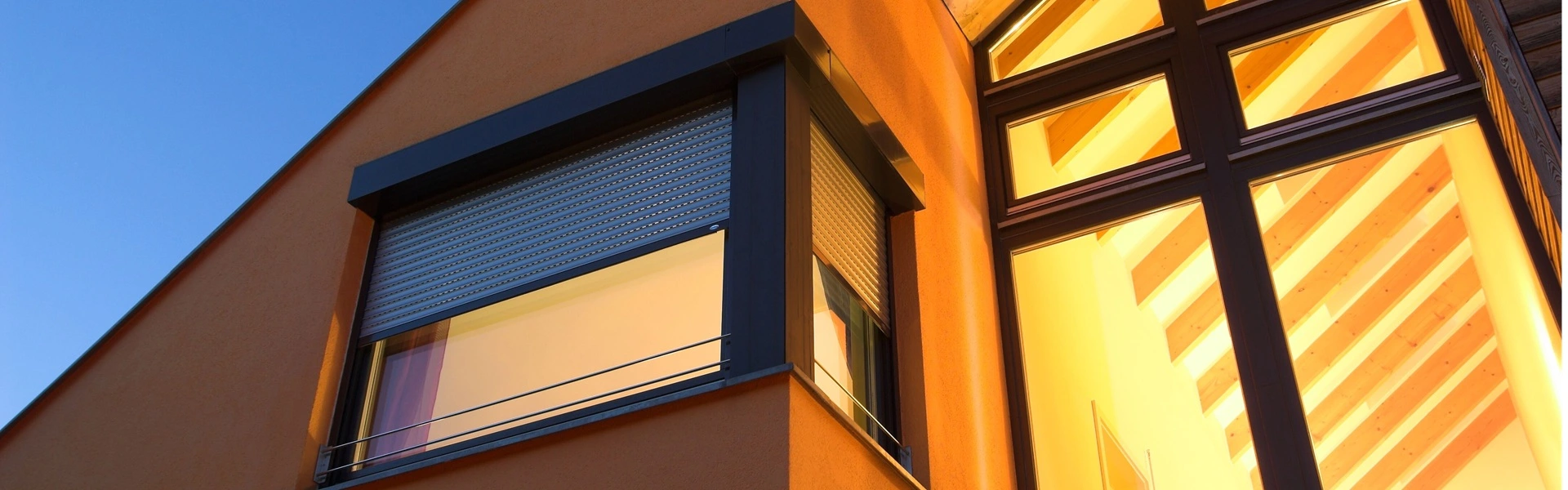 Roma rolluiken op een houten gevel van een duurzaam huis bij avondlicht