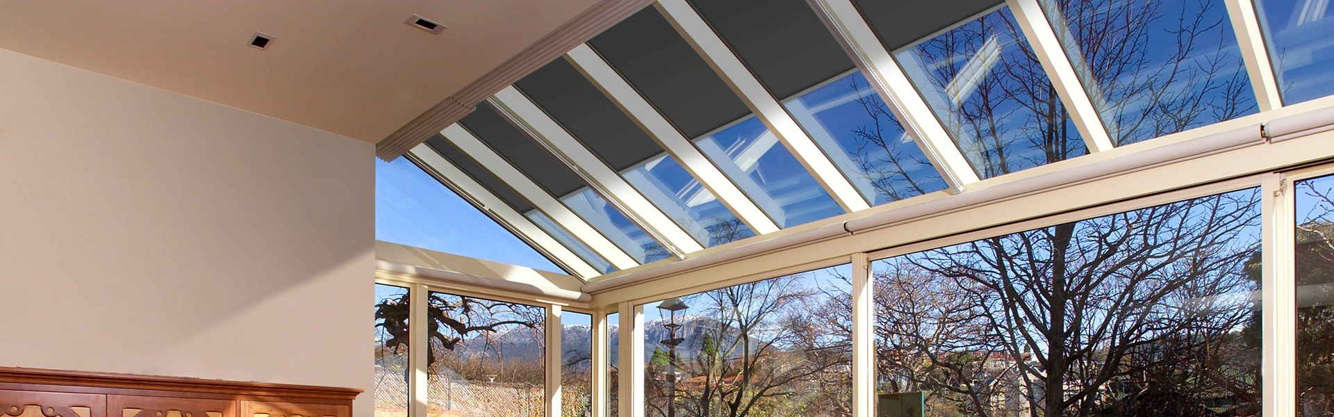 Serre zonwering VZ 0800 zip solar gemonteerd in een glazen serre met buitenzicht