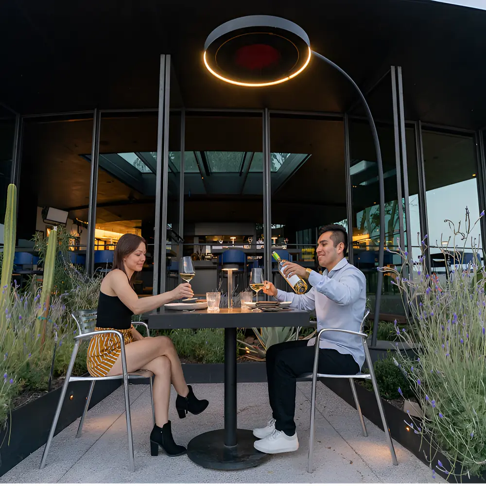 Stel dineert onder een draagbare heater in een elegante tuinsetting