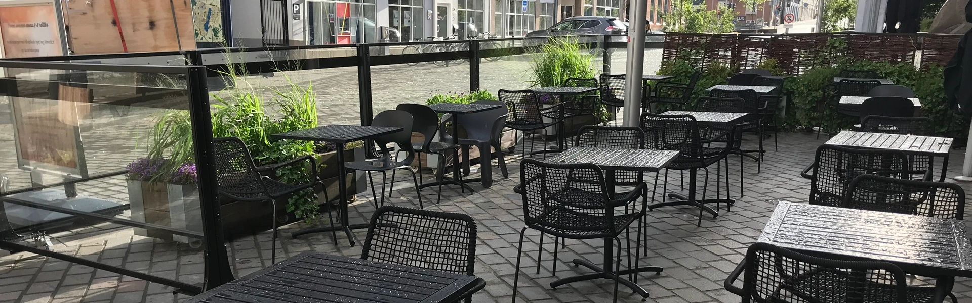 Terrasopstelling met glaswanden en groene accenten in een stedelijke setting