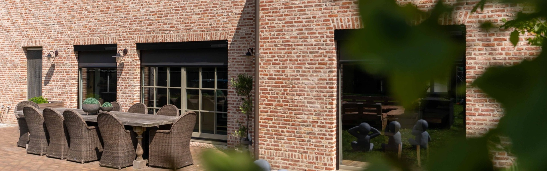 Traditionele bakstenen gevel met twee Cool Screen Solar screens en houten eettafel