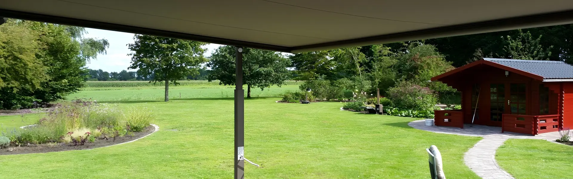 Uitzicht vanaf een overkapping met doek Plaza Viva op een tuin met gras