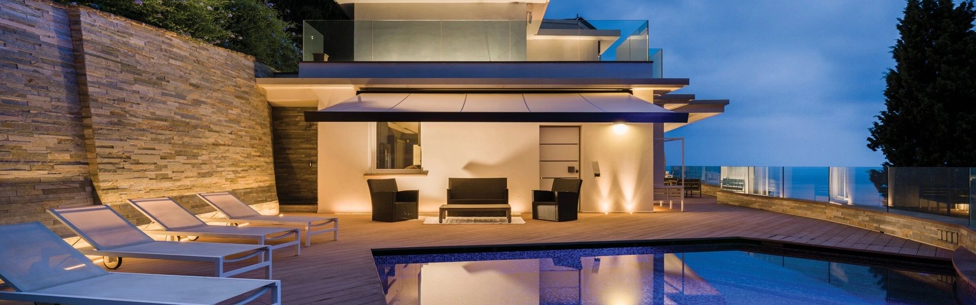 Verlicht knikarmscherm Nodo bij luxe villa met zwembad in de avond