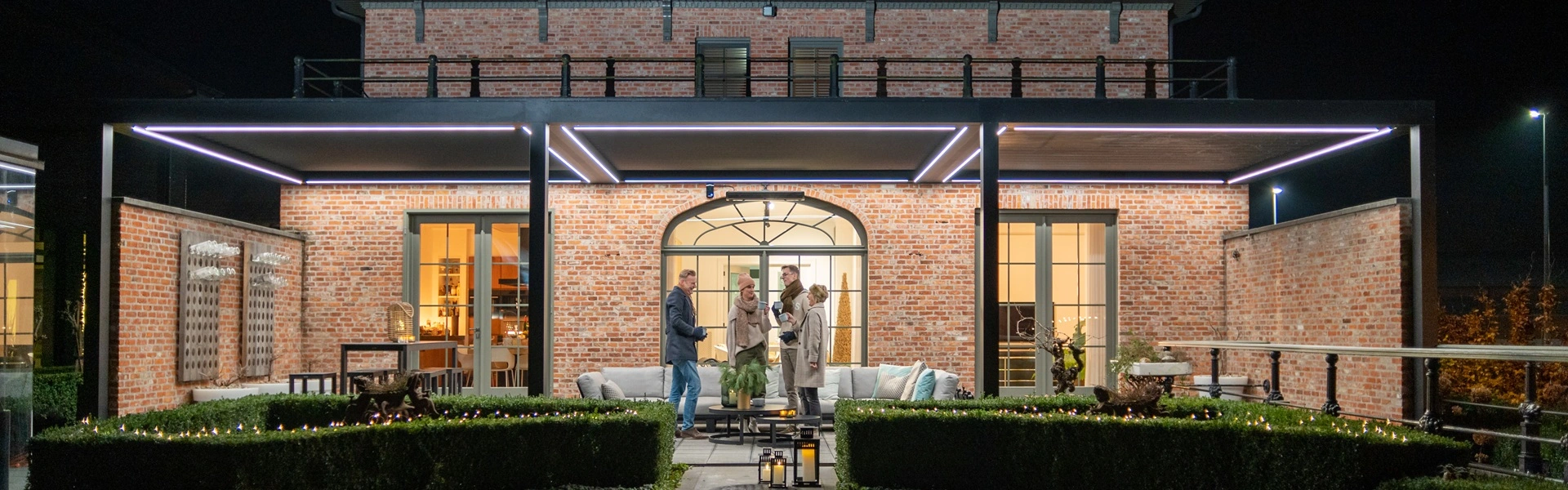 Verlichte Brera lamellenoverkapping tijdens de avond boven een sfeervol terras