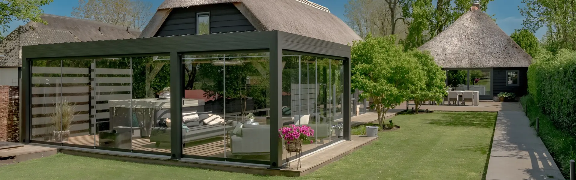 Vrijstaande tuinkamer met lamellen naast een rietgedekte schuur