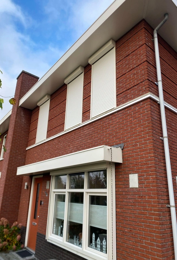 Witte rolluiken op een rode bakstenen woning in Heerenveen Witte rolluiken op een rode bakstenen woning in Heerenveen