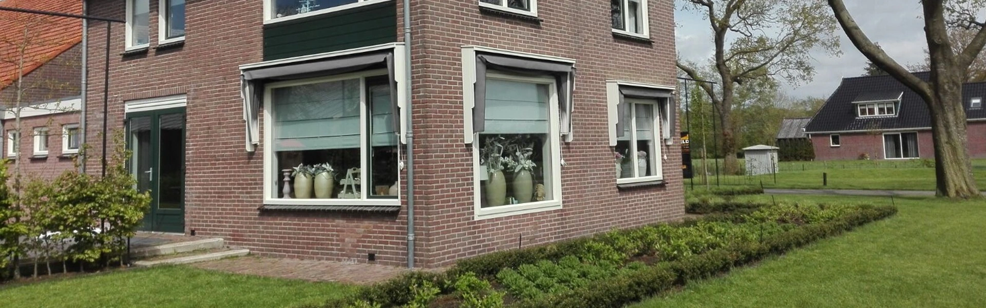 Woning met opgehaalde grijze markiezen op de ramen en een tuin