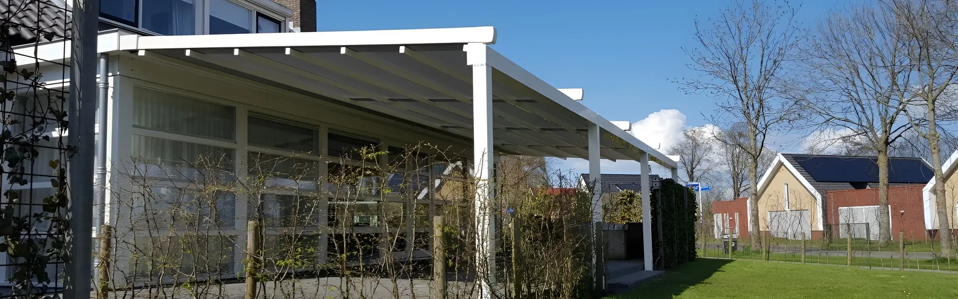 Zijkant van de Pergotex overkapping met doek en groene heg op terras