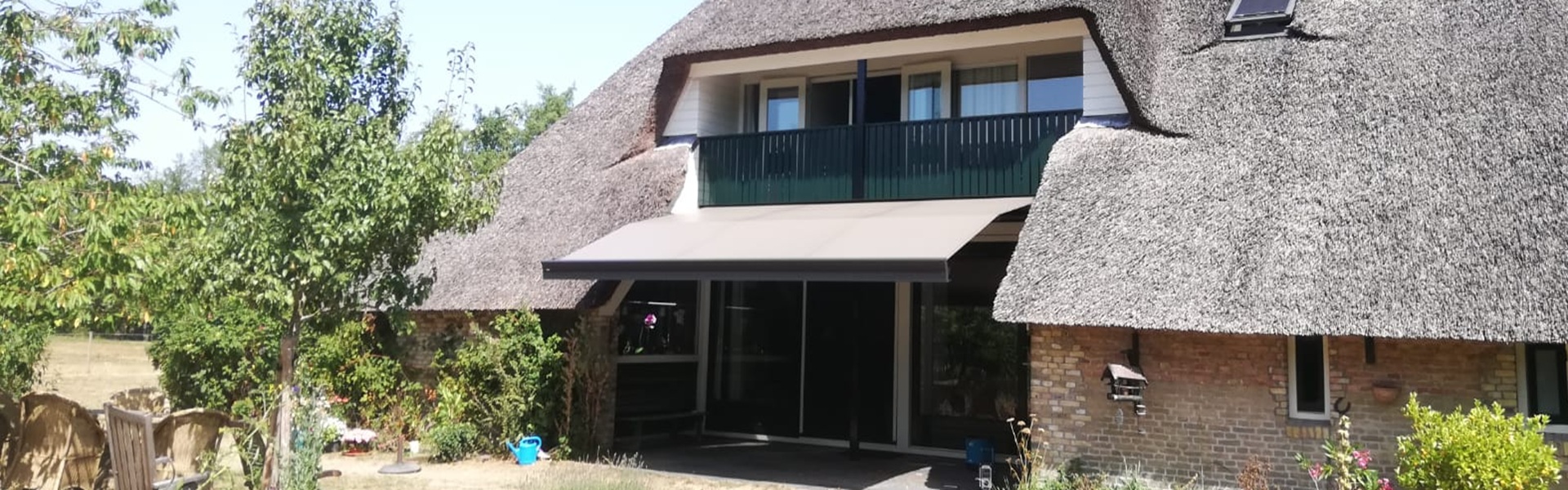 Zon en regenwering ZRS op maat, geplaatst onder een rieten dak