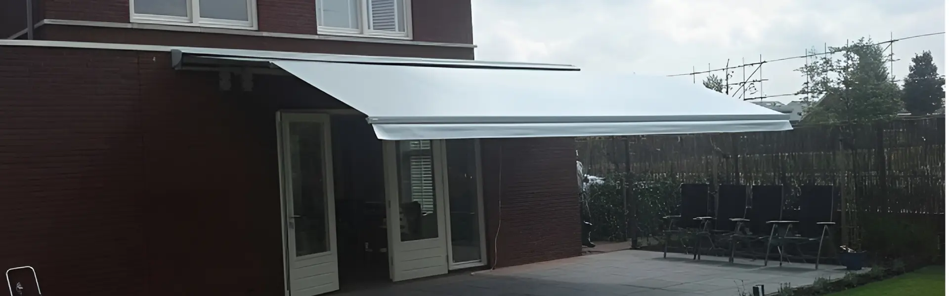 Zon en regenwering type L met uitzicht op tuin en water, beige doek