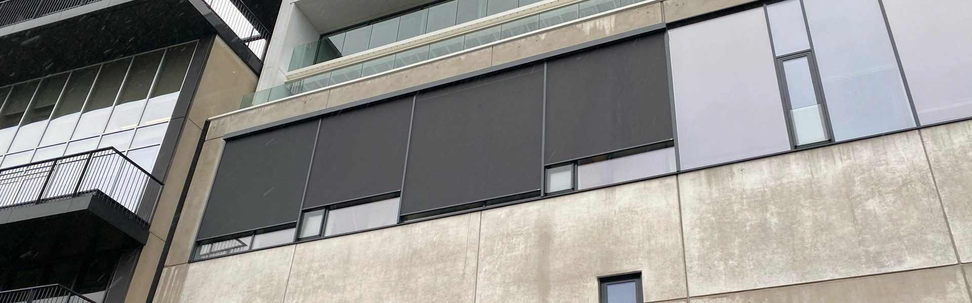 Zwarte zonnescreens geplaatst op een betonnen gevel voor optimale zonwering