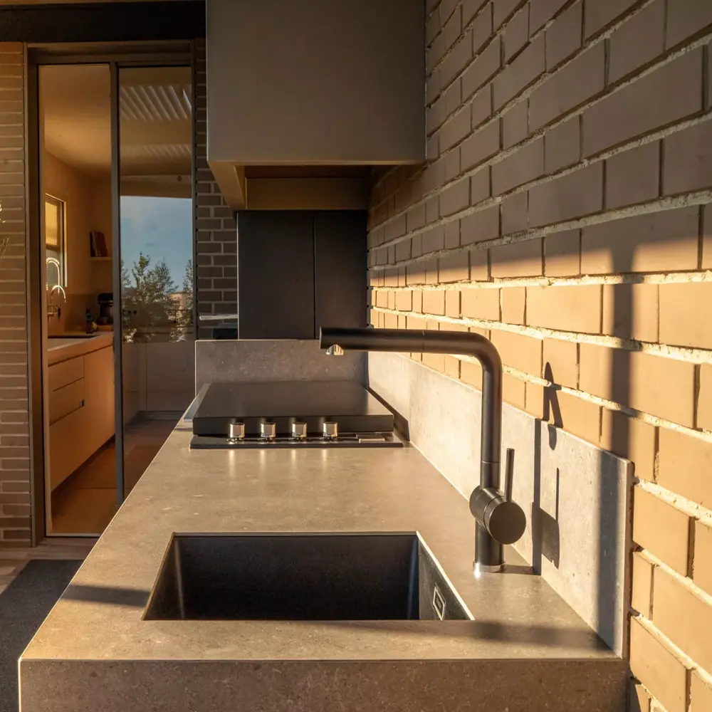 Close-up van Novara buitenkeuken met stenen blad en zwarte kraan