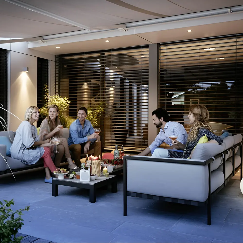 Gezin geniet van maaltijd buiten onder elektrische zonwering van Somfy