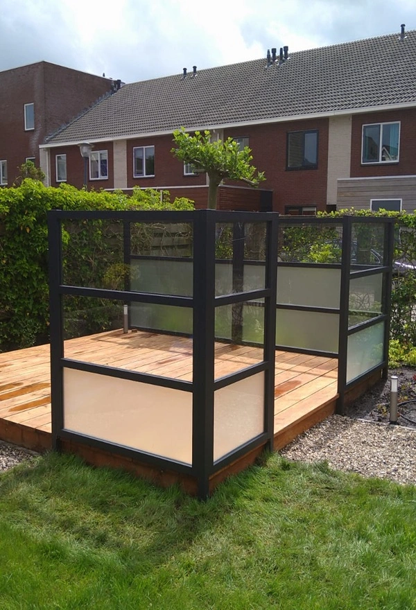 Glazen windscherm op houten terras in Leeuwarden door Veldman Zonwering, beschermt tegen wind Glazen windscherm op houten terras in Leeuwarden door Veldman Zonwering, beschermt tegen wind