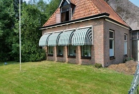 Groen-wit gestreepte markiezen op een bakstenen woning