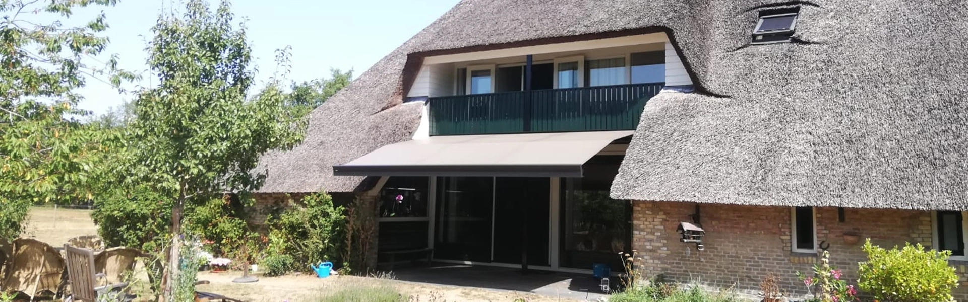 Rietgedekt huis met stijlvol zon- en regenscherm in Reis, door Veldman Zonwering Rietgedekt huis met stijlvol zon- en regenscherm in Reis, door Veldman Zonwering