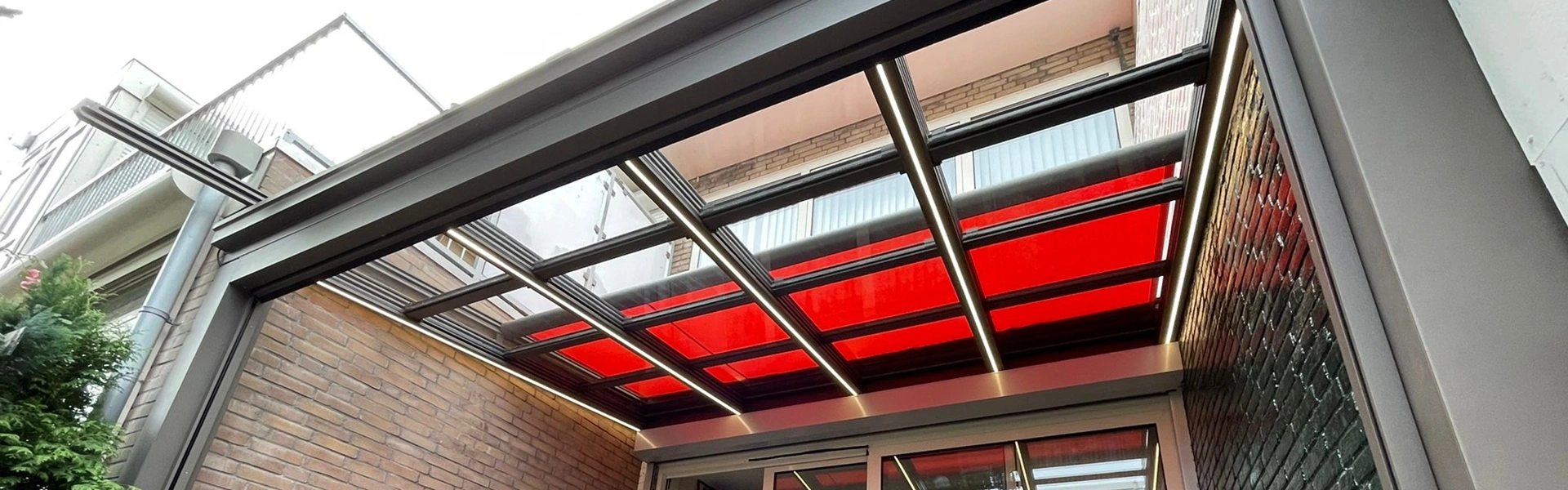 Schuifbaar glazen dak met rode zonwering, geplaatst door Veldman Zonwering in Amsterdam