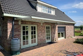 Traditioneel huis met knikarmscherm voor terrasoverkapping