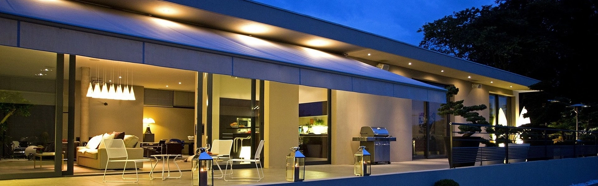 Verlicht terras met elektrische zonwering en zwembad in de avond