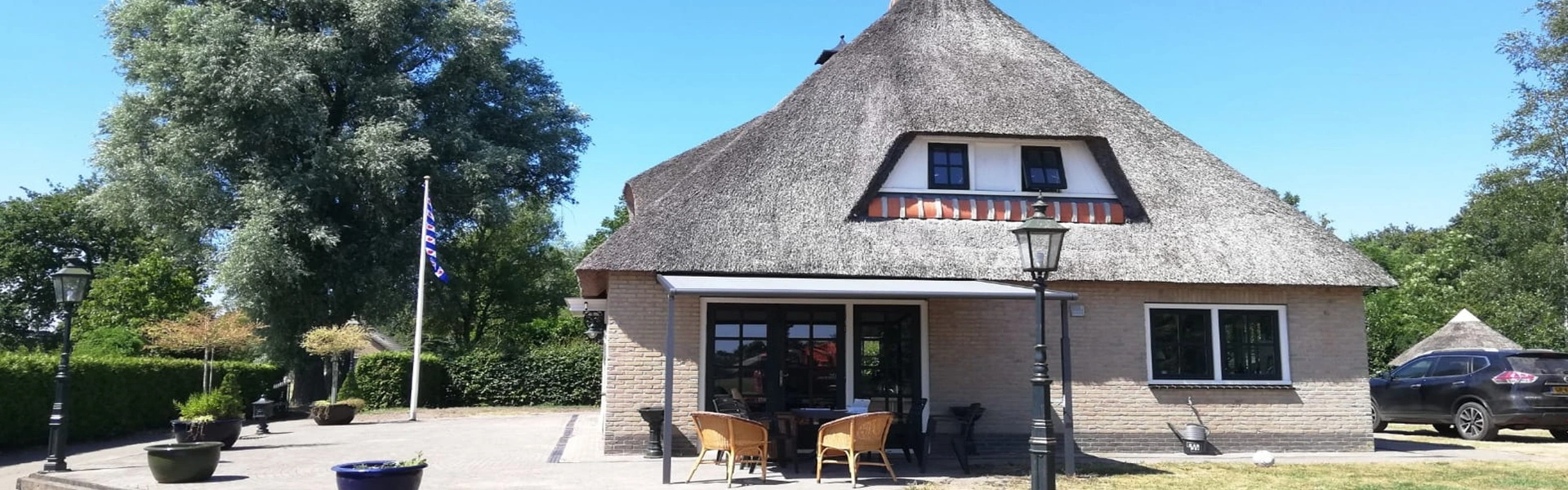Woning met rieten dak en terras met zonwering door Veldman Zonwering Woning met rieten dak en terras met zonwering door Veldman Zonwering