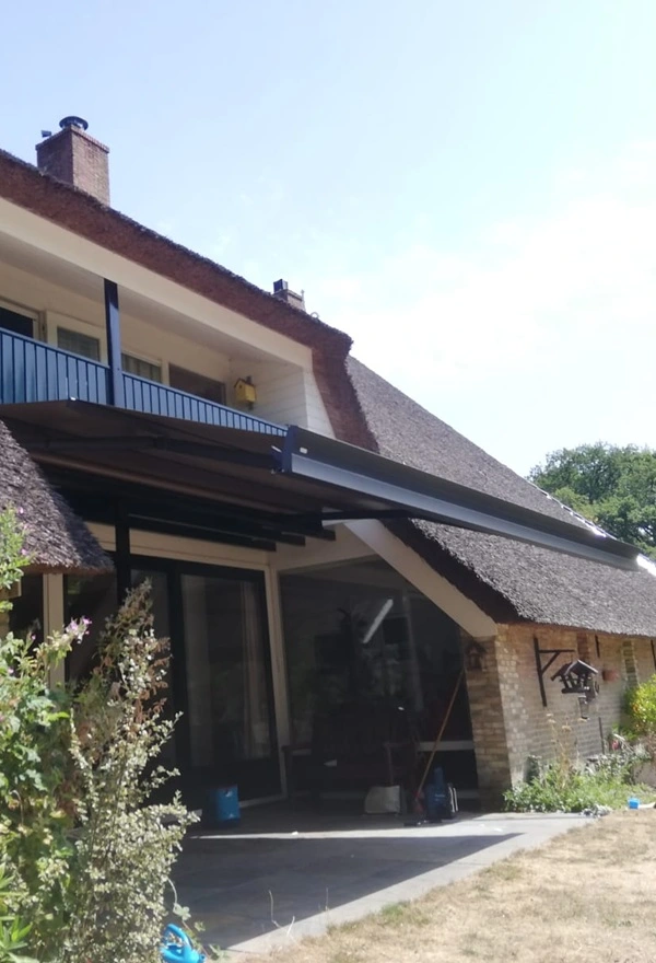 Zon- en regenscherm aan rietgedekt huis in Reis door Veldman Zonwering Zon- en regenscherm aan rietgedekt huis in Reis door Veldman Zonwering