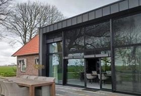 Zwarte buitenjaloezieen op moderne gevel met houten tafel