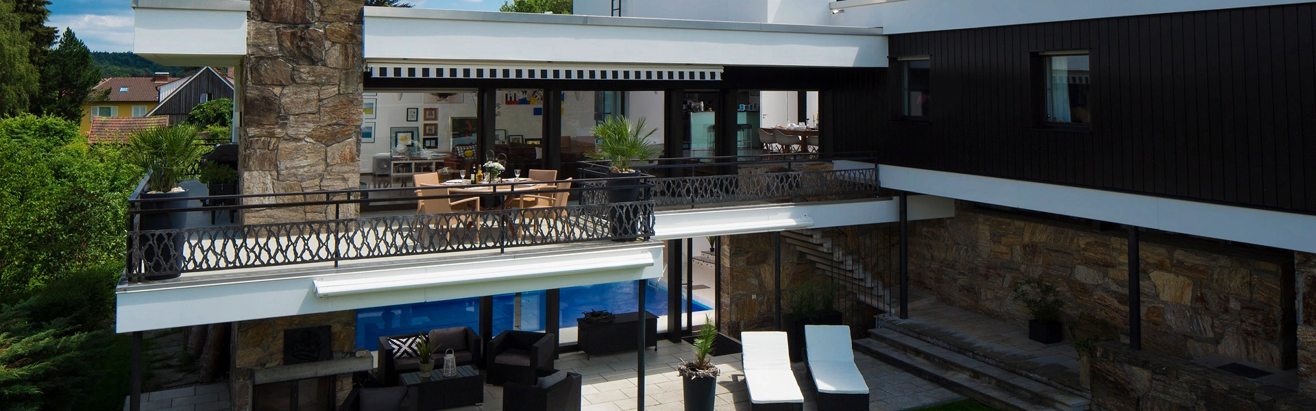 Ingerolde cassette zonneschermen boven terras met ligstoelen en loungehoek