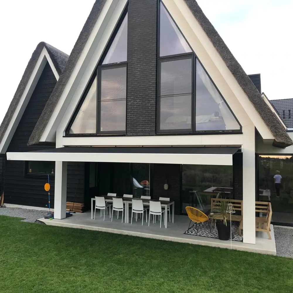 Woning met rieten dak en knikarmscherm boven terras