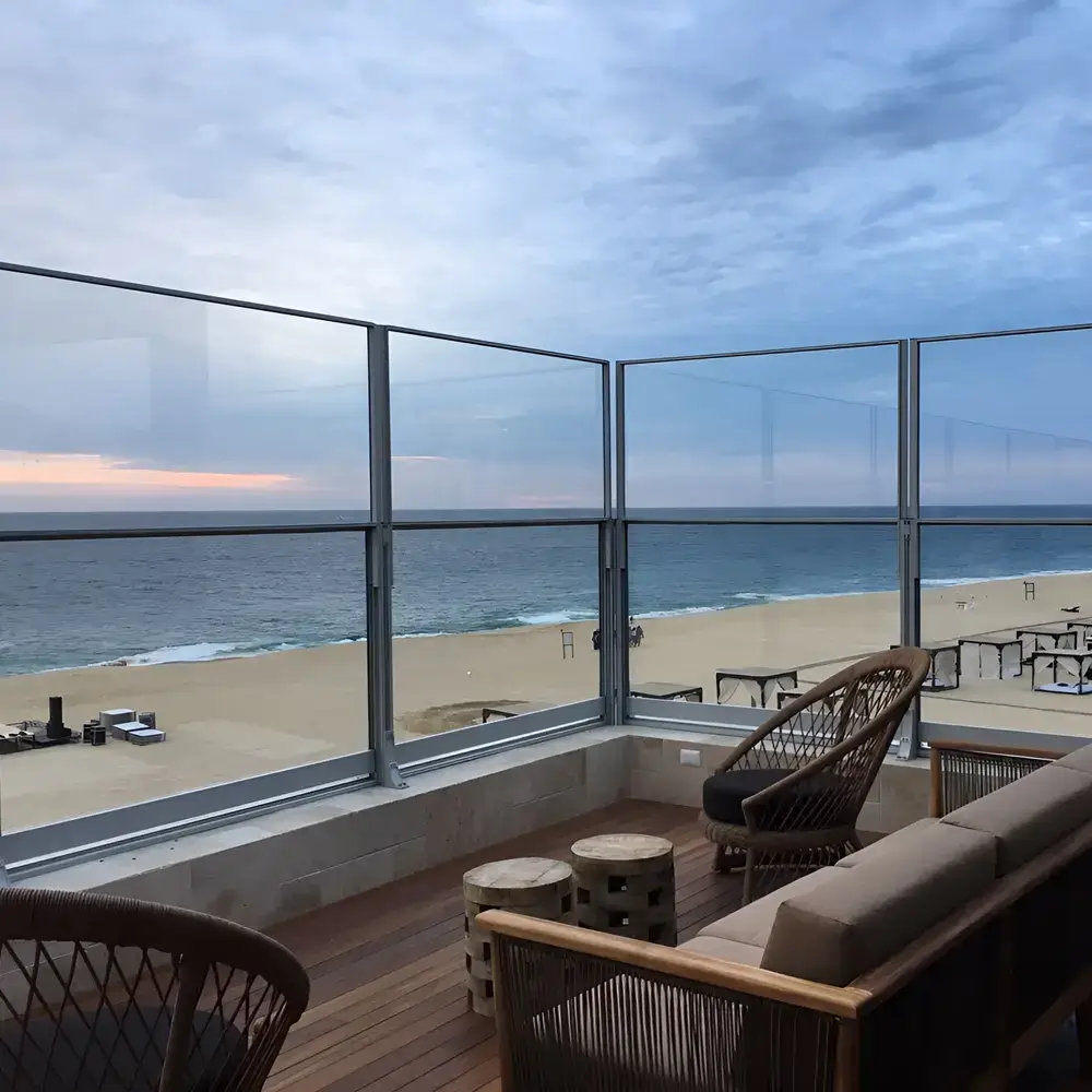 Glazen windschermen op terras in Griekenland met uitzicht op zee en zonsondergang