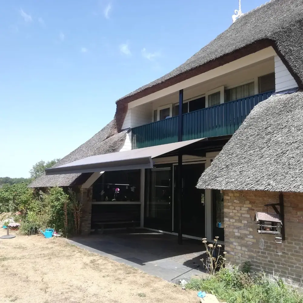Rietgedekt huis met zon en regenscherm in Reis geplaatst door Veldman Zonwering 2